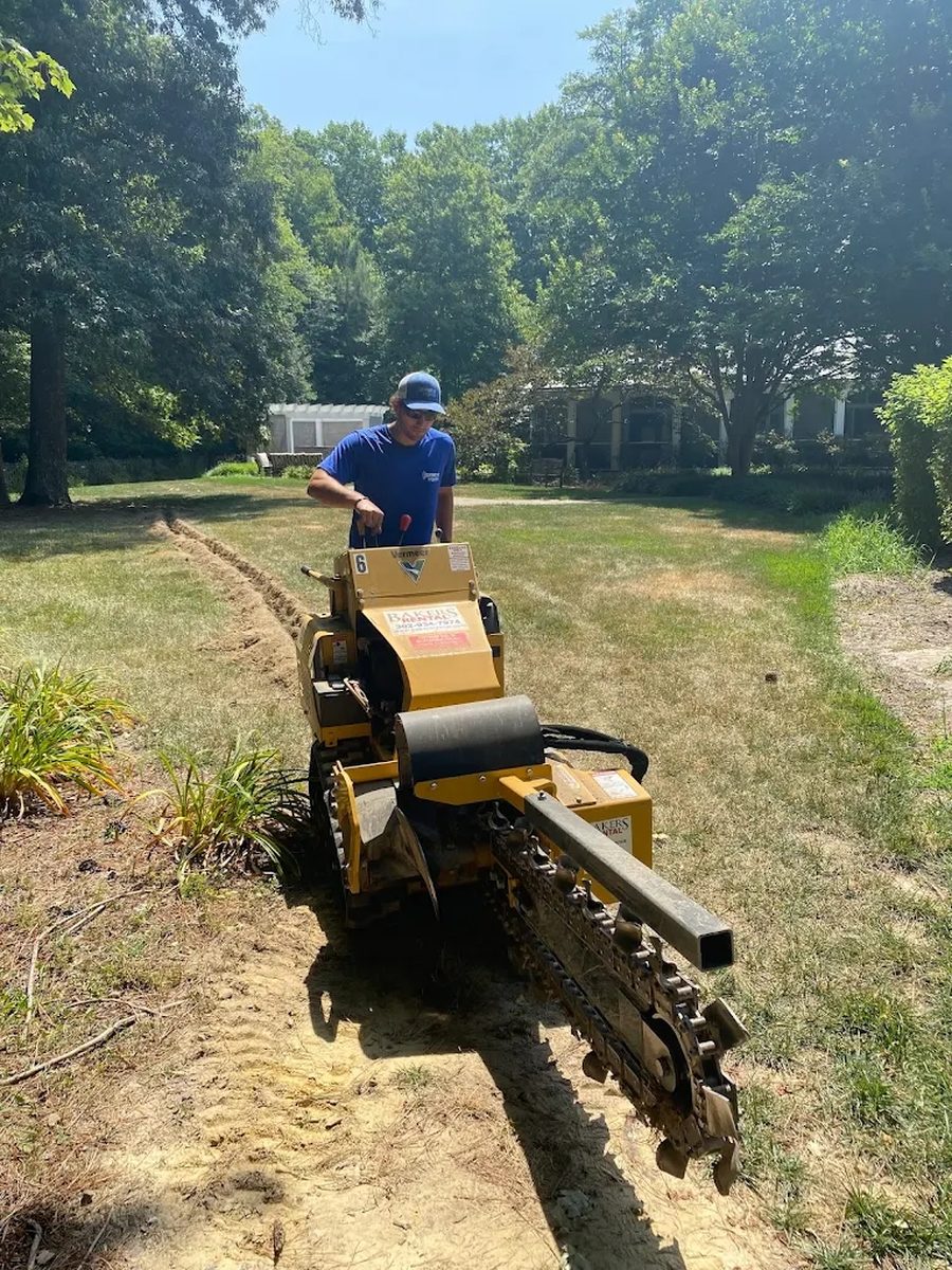 Ethan Ghabra, founder of ServiceAlly, operating a trencher on an irrigation job at a Delaware property